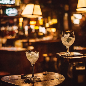 a glass of gin tonic on a wood table in a jazz bar in the heart of Manhattan, in wong kar wai movies style.