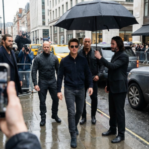 Create a photorealistic and highly detailed image featuring the attached image walking confidently down a modern city street, accompanied by Jason Statham, Dwayne “The Rock” Johnson, and Jason Momoa acting as bodyguards.

John Wick (Keanu Reeves) is walking just beside or slightly behind the subject, holding an umbrella over him to shield from light rain.

The subject should be the central figure, wearing stylish casual clothing — like a fitted jacket, dark jeans, and sunglasses — exuding calm authority and cool charisma.

Statham, The Rock, and Momoa are dressed in black tactical-style suits, maintaining alert, protective stances, scanning the surroundings like professional bodyguards. John Wick wears his signature black suit and tie, looking composed as he holds the umbrella.

The setting is a downtown urban street with wet pavement reflecting city lights, parked luxury cars, and paparazzi in the background snapping photos.

The photo should look like a real paparazzi shot — slightly off-angle, mid-step motion blur, with realistic lighting and reflections.

Lighting: natural daylight with overcast skies, reflections from wet concrete, realistic shadows, subtle raindrops on the umbrella and clothing.

Camera realism: crisp detail on facial features and clothing textures, shallow depth of field emphasizing the group, with lens flare or light bloom for authenticity.

Mood & tone: grounded, cinematic, and stylish — feels like a moment from a celebrity entourage photo or action-movie press capture, taken with an iPhone by paparazzi.

Style: ultra-realistic, documentary-style street photography with modern cinematic sharpness.