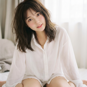 Certainly! Here is your enhanced, artistic, and detailed prompt for an AI image generator:

---

A captivating portrait of a young Asian woman, inspired by Imada Mio and embodying an exquisitely delicate, doll-like (精緻洋娃娃臉) aesthetic. She has large, round, expressive eyes that radiate innocence and curiosity, subtly accented with a moist shimmer. Her petite V-line face is framed by soft, rosy cheeks, and her lips are naturally pink and slightly parted, exuding an energetic, slightly flirty, yet pure aura. Her expression is a candid blend of sweetness and playful allure.

Her long, dark brown hair is artfully tousled with a messy morning (剛睡醒的凌亂感) effect—loose strands fall gently around her face, conveying natural volume and effortless beauty. The hair has a silky texture, catching the light in places, suggesting a recent awakening.

She is dressed in an oversized, translucent white button-down shirt (男友風白襯衫) with the top buttons casually undone, delicately revealing her collarbones and a slender neckline. The shirt drapes loosely, giving a tasteful "bottomless" look (下衣失蹤風格), her bare legs just barely visible beneath the shirt's hem, enhancing the innocent-meets-sensual ambiance.

The composition is styled in the manner of a Japanese Gravure Photobook (寫真集風格), exuding a pure & sexy vibe with an airy, dreamy atmosphere. Employ bright, high-key lighting for a clean, luminous effect that highlights her velvety soft skin texture. Use Fujifilm PRO 400H film tones for subtle pastel hues, gentle contrast, and a seamless blend of natural colors, further enriching the soft, ethereal, and intimate photographic quality.

The background is minimalist and softly blurred, ensuring complete focus on the subject, and enhancing the overall sense of warmth, comfort, and inviting allure typical of high-end Japanese photobooks.

---