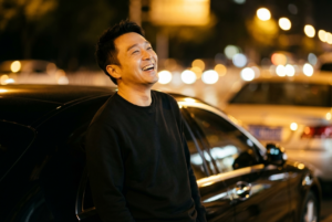 Google Gemini / Meta AI 🎯💯 

Promte ✅ 

A hyper-realistic night portrait of a handsome young man leaning casually against a black luxury car, laughing heartily with head tilted slightly back. He has a groomed beard, short styled dark hair, and is wearing a plain black long-sleeve crewneck sweatshirt. The lighting is low-key and cinematic, with the subject's face warmly illuminated against the darkness. The background features a dark street with beautiful, creamy golden bokeh orbs from distant streetlights and car headlights. Shot on a Sony A7R IV with an 85mm f/1.4 lens, shallow depth of field, sharp focus on the smile, high contrast, moody urban night atmosphere, 8k resolution. Size 4:5 ratio 100% use my upload reference image